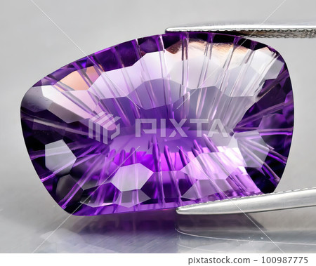 Natural gemstone purple amethyst on gray background 100987775