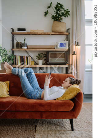Young woman scrolling her smartphone in the apartment. Young woman scrolling her smartphone in the apartment. 100988053