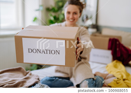 Young woman giving her clothes to charity. Young woman giving her clothes to charity. 100988055