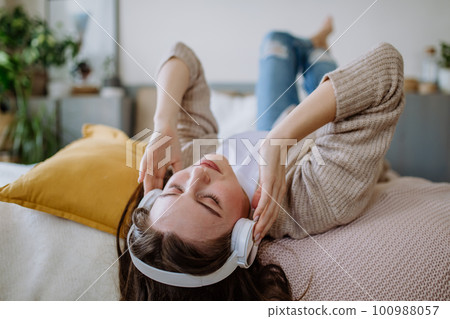 High angle view of young woman listening music trough headphones. High angle view of young woman listening music trough headphones. 100988057