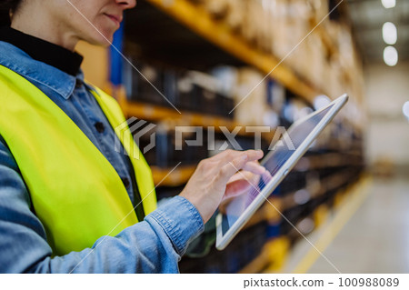 Warehouse female worker checking up stuff in a warehouse. 100988089