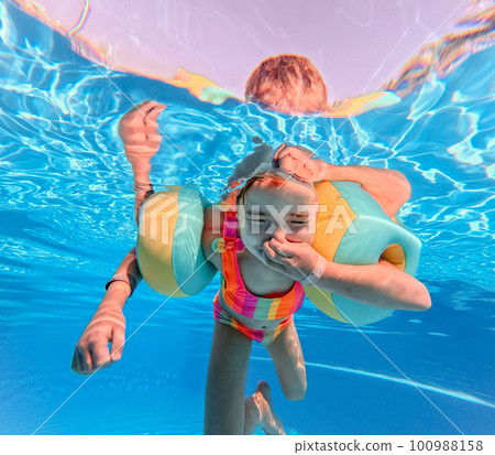 Little girl in swimsuit diving in swimming pool. Little girl in swimsuit diving in swimming pool. 100988158