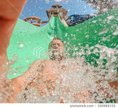 Close-up of man on water slide, enjoying summer time. Close-up of man on water slide, enjoying summer time. 100988159