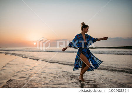 Young woman enjoying time at sea, dancing. 100988234