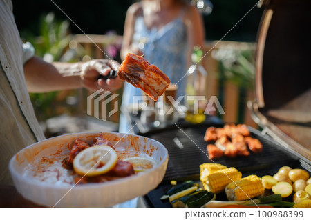 Unrecognizable man preparing meat and vegetables for grilling during family summer garden party, close-up Unrecognizable man preparing meat and vegetables for grilling during family summer garden party, close-up 100988399