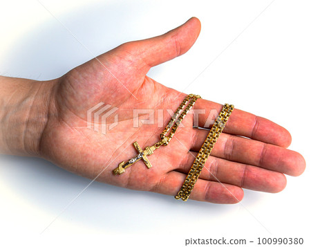 Christian cross with a gold chain on the palm of a man. 100990380