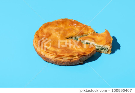 Phyllo spinach pie isolated on a blue background. Savary pie with spinach and cheese 100990407