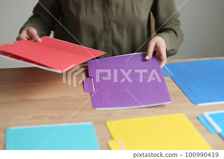 Employee puts multi-colored folders with files and documents 100990419