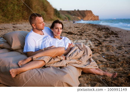 Young couple wrapped in a blanket outdoors. 100991149