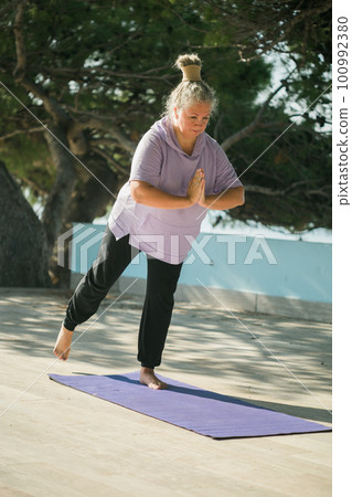 Mature woman with dreadlocks working out doing yoga exercises on sea beach copy space - wellness well-being and active elderly age concept Mature woman with dreadlocks working out doing yoga exercises on sea beach copy space - wellness well-being and active elderly age concept 100992380