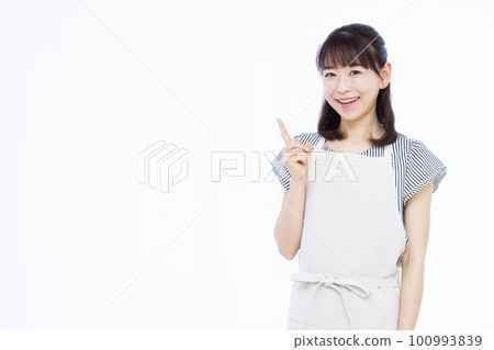 A housewife in her thirties wearing an apron pointing A housewife in her thirties wearing an apron pointing 100993839