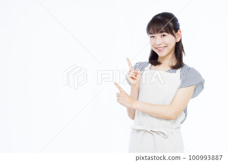 一位三十多歲的家庭主婦穿著圍裙指著她的手指 一位三十多歲的家庭主婦穿著圍裙指著她的手指 100993887