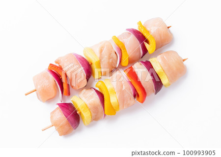 Skewers with pieces of raw meat, red, yellow and green pepper.Raw pieces of chicken skewers with pepper onion and pineapple on a white background.Top view.Uncooked mixed meat skewer with peppers. 100993905