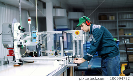 worker of printing equipment, adjusts, regulates the printing process. working process of printing packages for grain, agricultural products. Conveyor belt. The work of modern printing equipment worker of printing equipment, adjusts, regulates the printing process. working process of printing packages for grain, agricultural products. Conveyor belt. The work of modern printing equipment 100994722