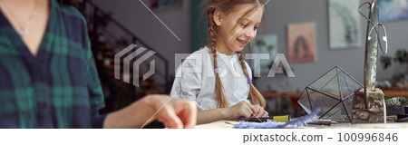 Flourist shop with different kinds of dryed flowers. Young happy confident specialist is working with her female kid. Flourist shop with different kinds of dryed flowers. Young happy confident specialist is working with her female kid. 100996846