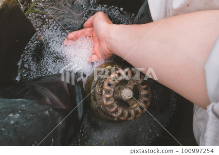 A farmer washing his feet at the water inlet of the rice field A farmer washing his feet at the water inlet of the rice field 100997254