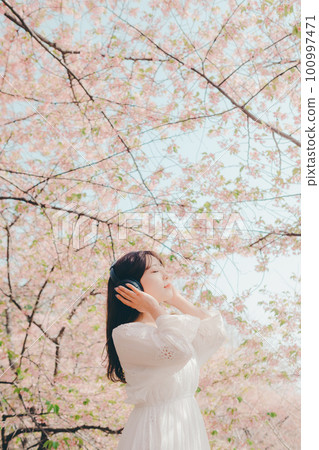 Woman listening to music under the cherry tree Woman listening to music under the cherry tree 100997471