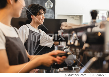 Male cafe staff serving coffee Male cafe staff serving coffee 100998276