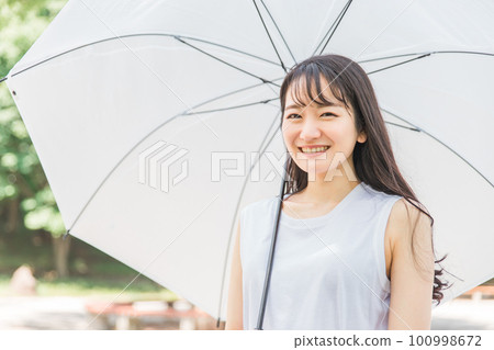 Asian woman holding an umbrella in the rainy season (smile, looking at the camera) 100998672