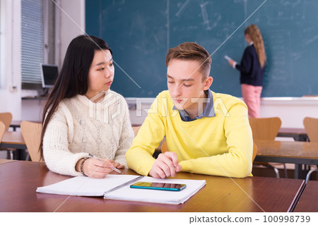 Chinese girl student helping friend prepare for exam 100998739