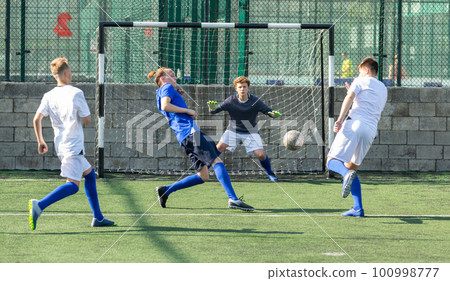 Youthful football players challenging for ball 100998777