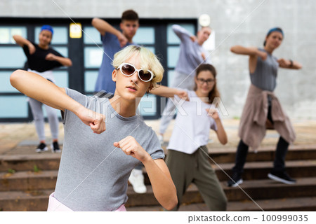 Modern teenager performing street dance with group 100999035
