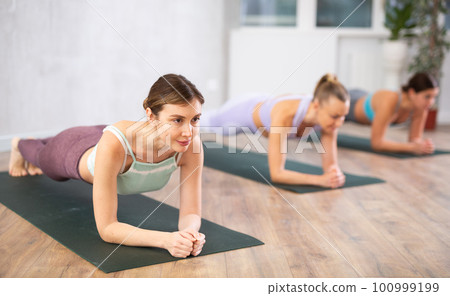 Girl with other sporty people relaxing and enjoying yoga in fitness center Girl with other sporty people relaxing and enjoying yoga in fitness center 100999199