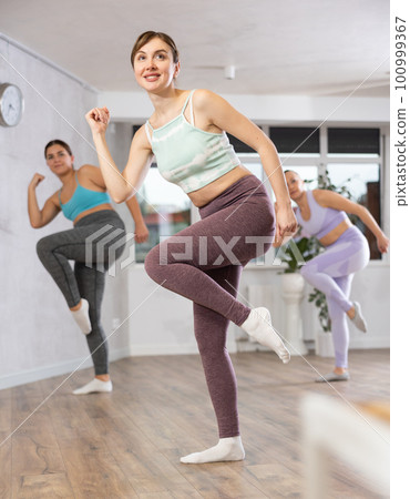 Cheerful young woman practicing energetic dance in choreography class 100999367