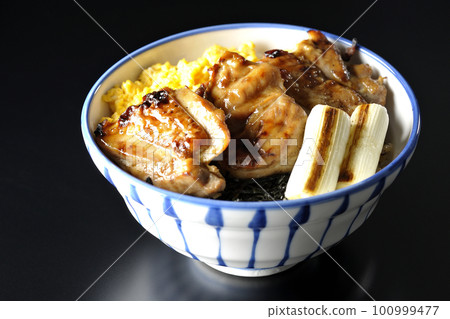 黑色背景中的照燒雞肉碗，上面放著碎雞蛋、烤蔥和切碎的海藻 100999477