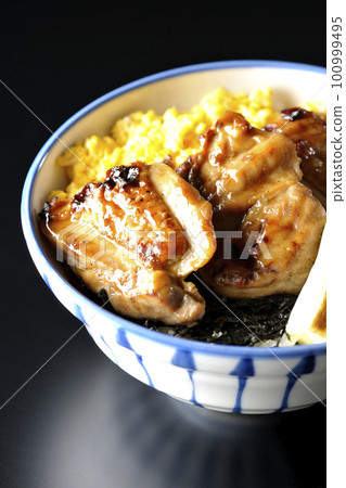 黑色背景中的照燒雞肉碗,上面放著碎雞蛋、烤蔥和切碎的海藻 黑色背景中的照燒雞肉碗,上面放著碎雞蛋、烤蔥和切碎的海藻 100999495