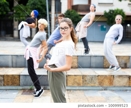 Teen girl street dancer performing with group outdoors 100999523