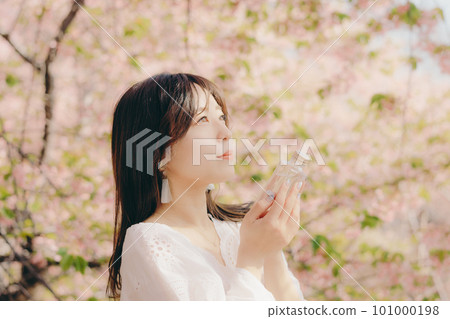 Woman holding a makeup bottle under the cherry blossom tree 101000198