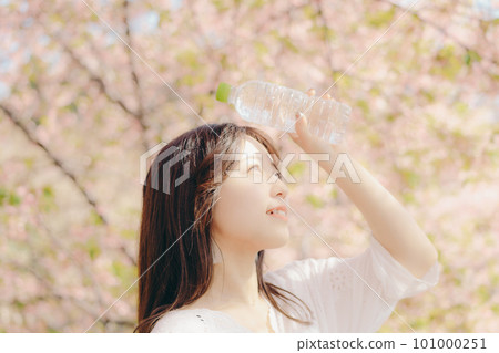 A woman holding a plastic bottle under the cherry tree 101000251