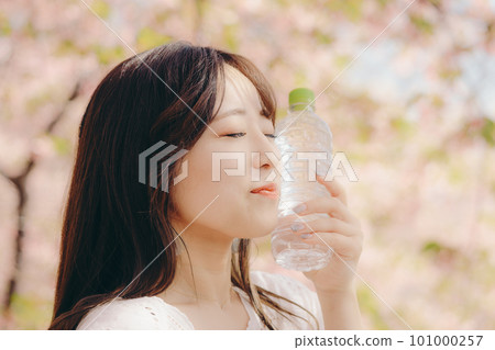 A woman holding a plastic bottle under the cherry tree 101000257