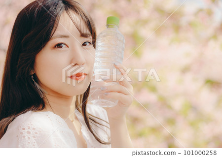 A woman holding a plastic bottle under the cherry tree 101000258