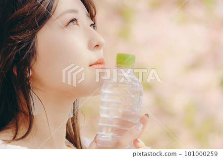 A woman holding a plastic bottle under the cherry tree 101000259