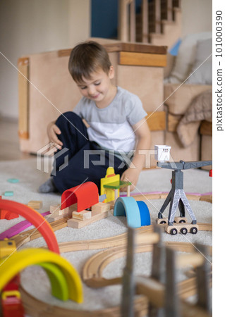 Preschool baby boy playing wooden Montessori materials rainbow arch railways at childish room 101000390