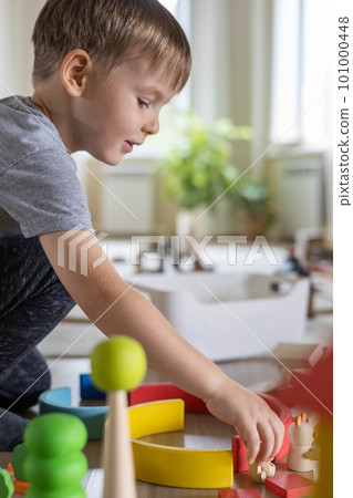 Confident male kid building fortress tower architecture wooden bricks ecology Montessori material 101000448