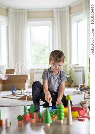 Confident male kid building fortress tower architecture wooden bricks ecology Montessori material 101000449