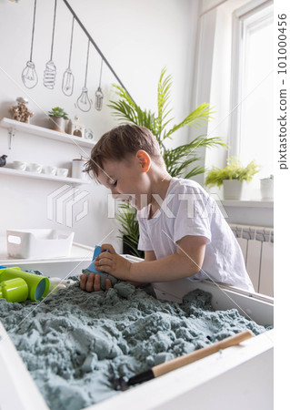 Overjoyed male kid playing kinetic sand early development education game fine motor skills 101000456