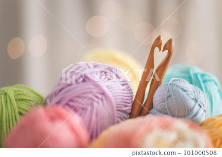 Cozy homely atmosphere. Heart from hooks for knitting. Yarn pastel multicolor in a basket. Skeins, balls, knitting needles, hooks and scissors. Cozy homely atmosphere. Heart from hooks for knitting. Yarn pastel multicolor in a basket. Skeins, balls, knitting needles, hooks and scissors. 101000508