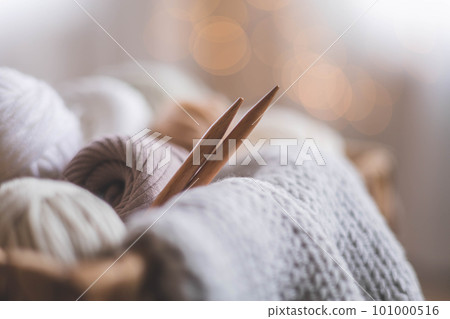 Cozy homely atmosphere. Female hobby knitting. Yarn in neutral shades in a basket woven from natural jute. Cozy homely atmosphere. Female hobby knitting. Yarn in neutral shades in a basket woven from natural jute. 101000516