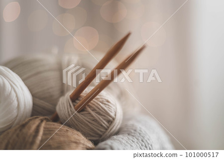 Cozy homely atmosphere. Female hobby knitting. Yarn in neutral shades in a soft basket of white and brown cord. Cozy homely atmosphere. Female hobby knitting. Yarn in neutral shades in a soft basket of white and brown cord. 101000517