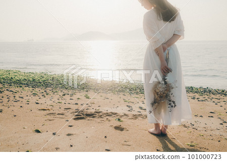 A woman holding dried flowers and staring at the sea A woman holding dried flowers and staring at the sea 101000723