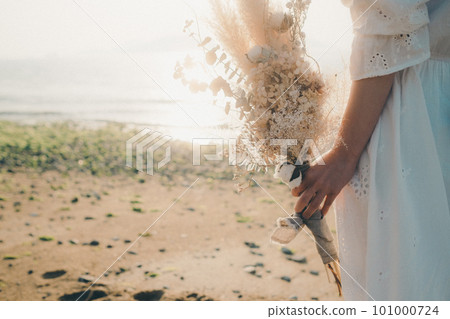 A woman holding dried flowers and staring at the sea 101000724