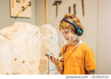 Boy looking at sculptures and listening to audio guide at museum exhibition Boy looking at sculptures and listening to audio guide at museum exhibition 101001418