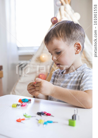 The child works with Montessori material with colored locks. Picks up keys. Develops fine motor skills. 101001558