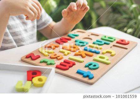 Male kid playing with wooden eco friendly alphabet letters board on table top view intellectual game 101001559