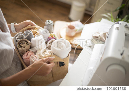 Woman seamstress choosing fabric textile material neatly folded eco basket electric sewing machine Woman seamstress choosing fabric textile material neatly folded eco basket electric sewing machine 101001588