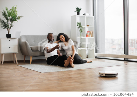 Multiethnic couple using remote control for vacuum cleaner Multiethnic couple using remote control for vacuum cleaner 101004484